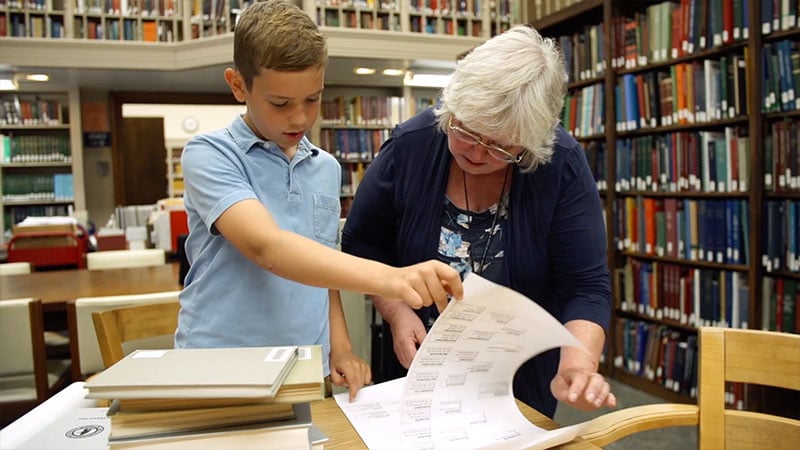 A young student looks over historical documents with a librarian.
