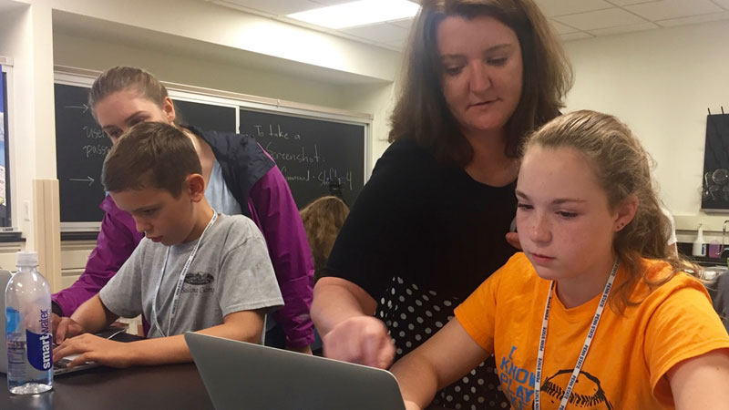 An instructor helps a student at her laptop during
				geneaological research.